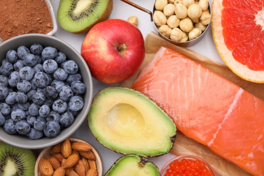 Berries, avocado, fruit, nuts and salmon on a white background