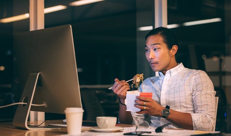 A man eats noodles at his table