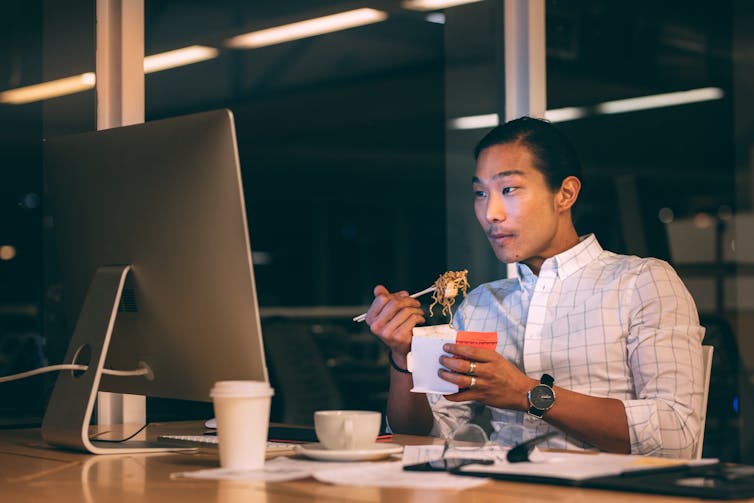 A man eats noodles at his table