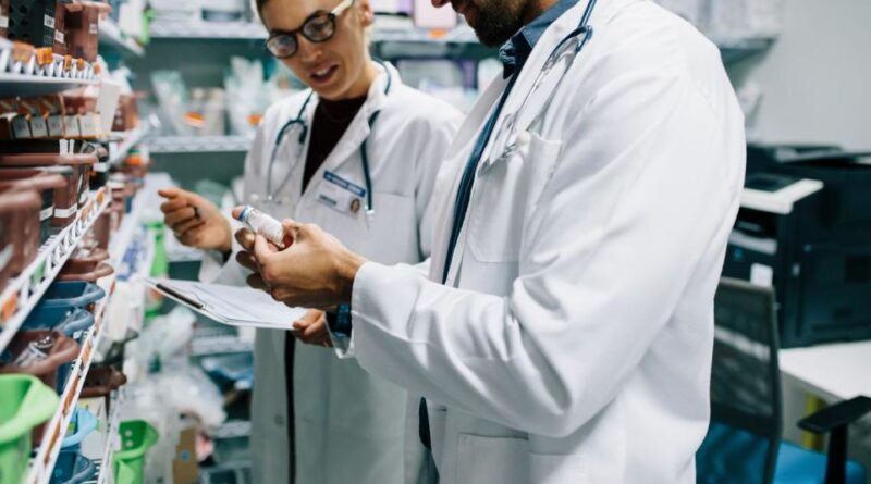 Two businessmen look at the vial.